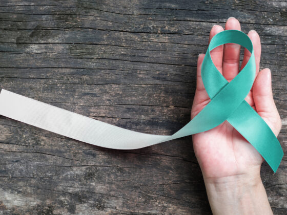 Krickente und weißes Band für Gebärmutterhalskrebs-Aufklärungskampagnenkonzept symbolische Schleife Farbe auf Frau helfende Hand Unterstützung auf altem Holz